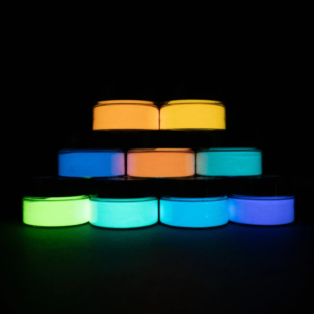 Nine horizontal bars of glow-in-the-dark brightest acrylic paint forming a vivid rainbow spectrum under low light