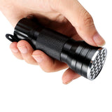 Hand holding a black uv 21 led flashlight with textured grip and metallic accent on a white background